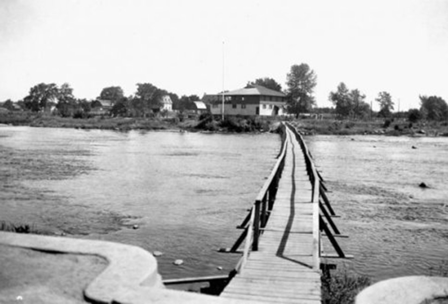 Archival black and white photograph showing a wooden footbridge across the river to Rideau Tennis Club.
