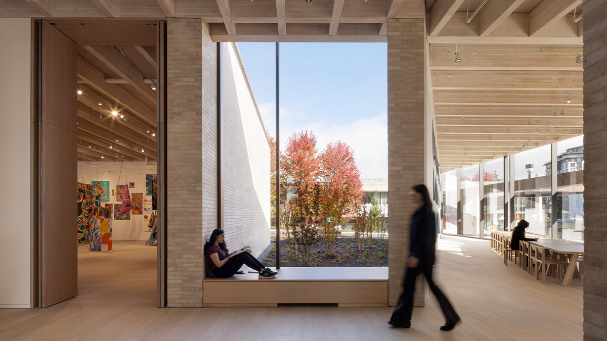 A large window in a sharply angled room with exposed roof structure and tan bricks