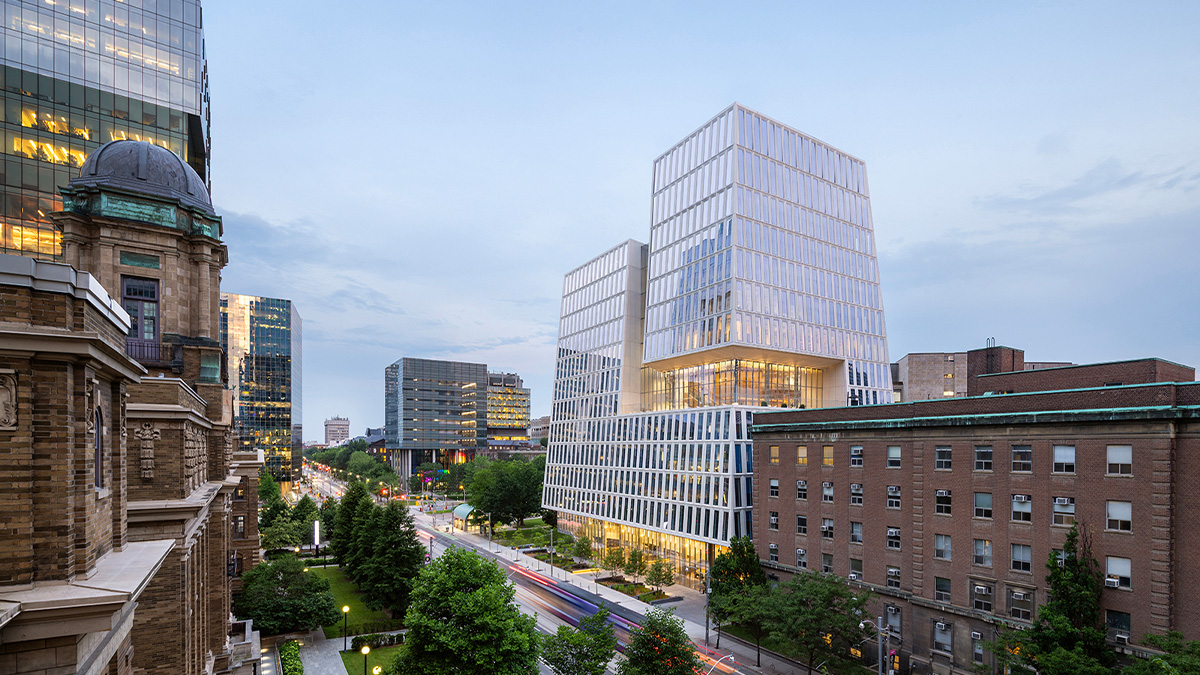 The exterior of a white angular building surrounded by lower brick buildings