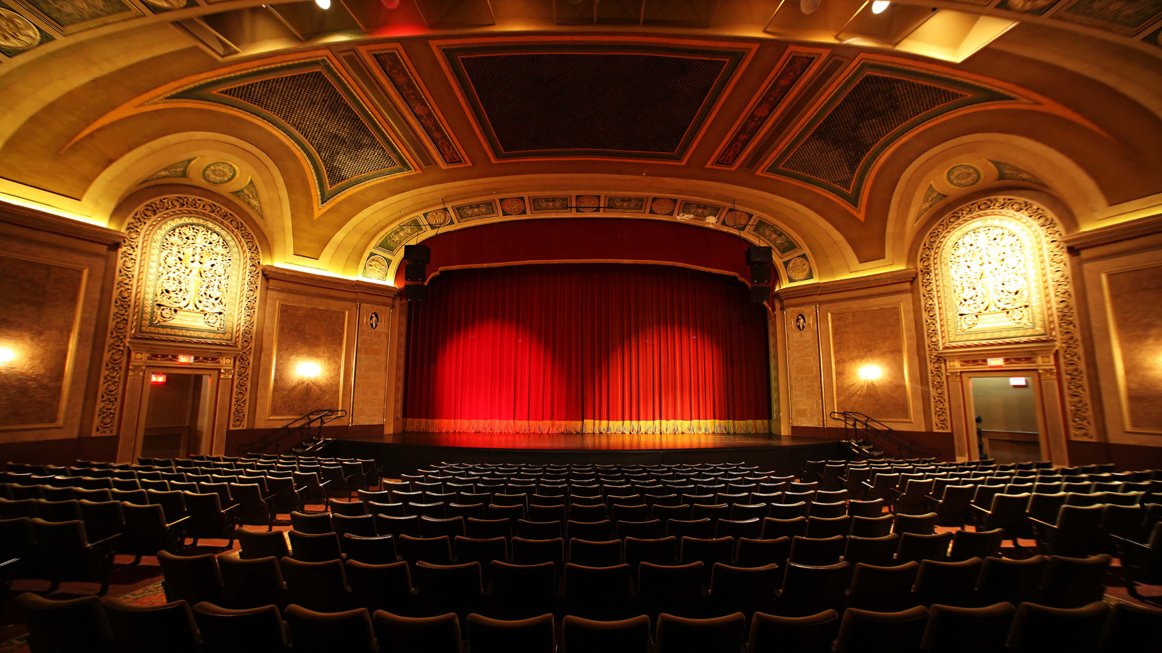 Interior view of Pentastar Theatre, the largest contemporary venue within Windsor’s Capitol Theatre featuring vaulted amber-coloured ceilings decorated with a border motif and a red velvet curtain.