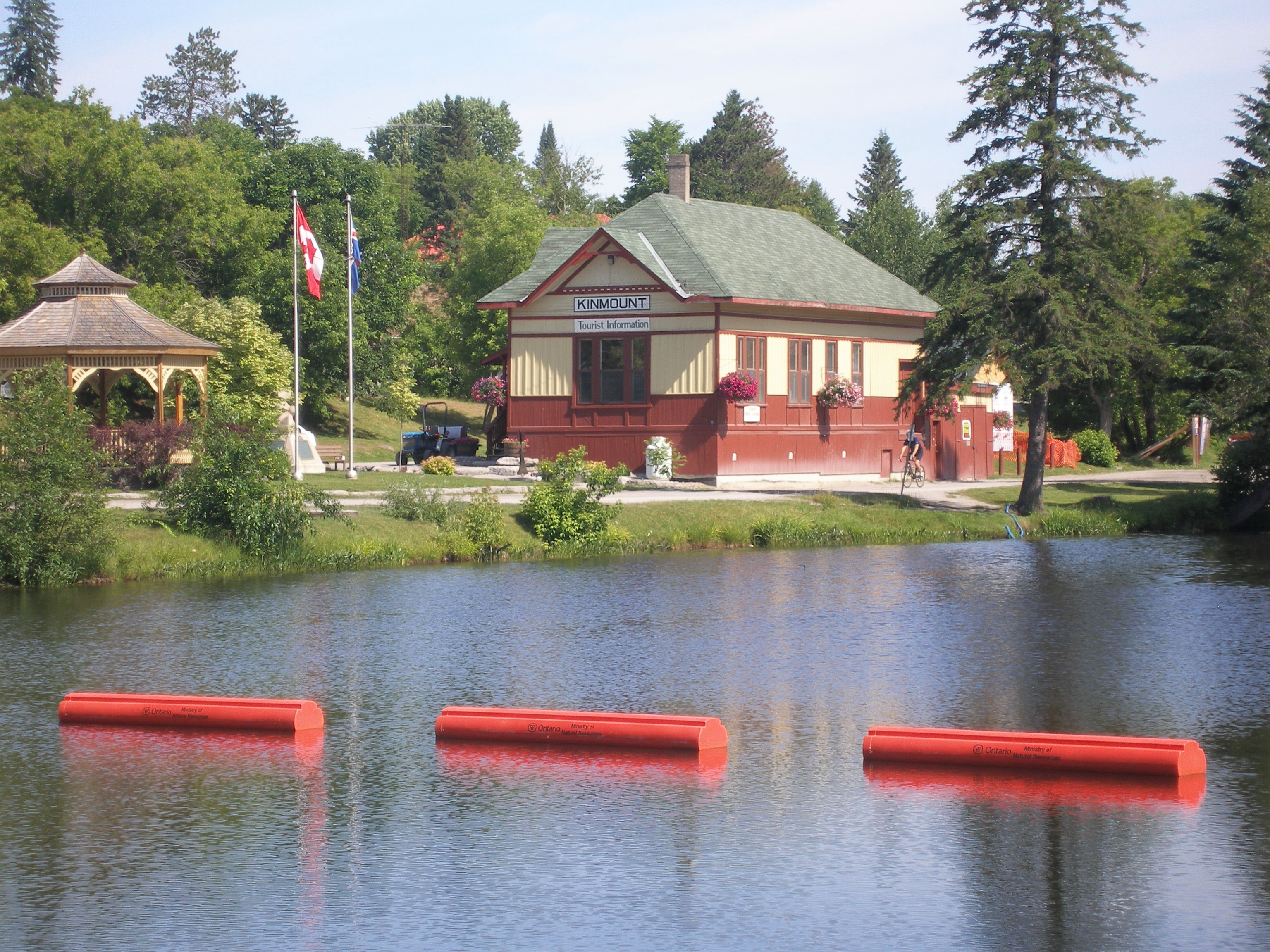 Small railway station with brightly-coloured exterior in a forested area alongside a river. 