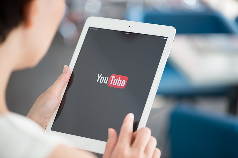 image of person holding a tablet with You Tube on the screen