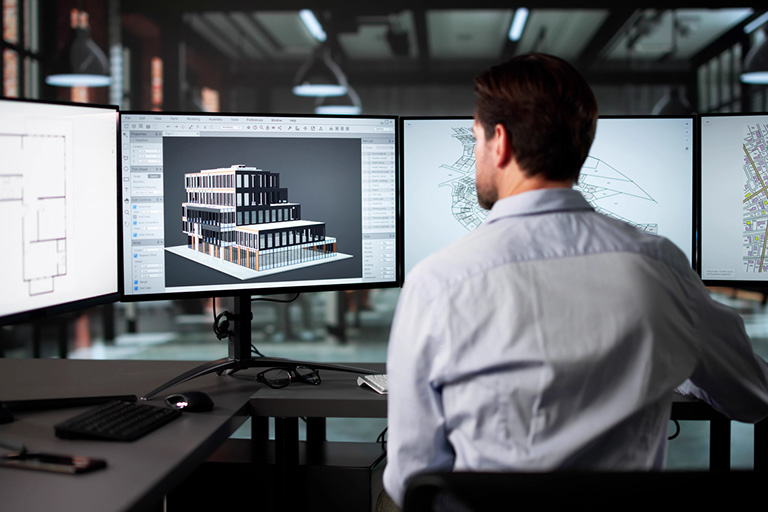 Man in front of 4 screens displaying a building rendering, plans and mapping/zoning grid 