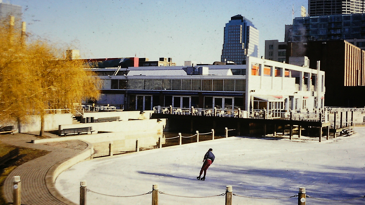An outdoor skating rink with a highrise in the backgroun