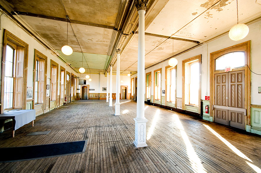 Interior space of the CASO station before renovation, featuring worn wooden floors, tall arched windows, and aged walls. It was popular for weddings and events despite its rough condition.