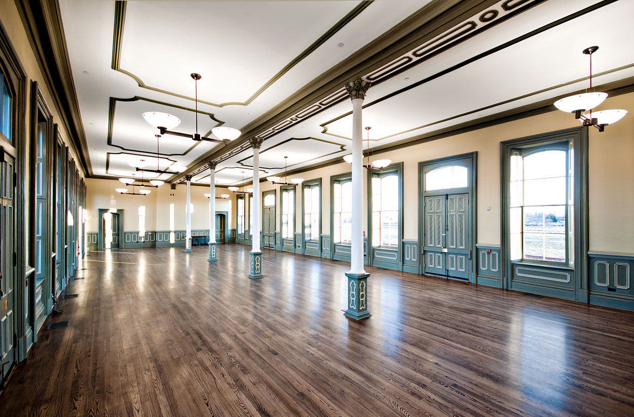 Renovated interior space of the CASO station, featuring wooden floors, teal trim, ornate columns, and updated lighting, bringing back colour and depth.