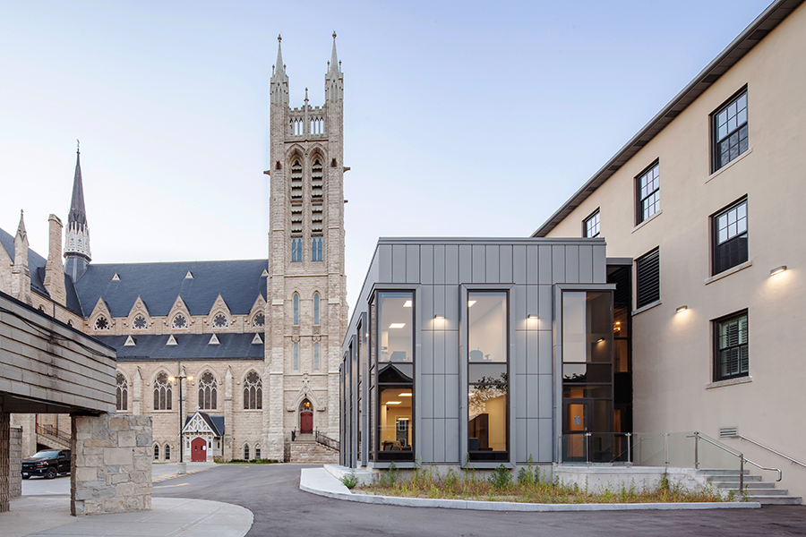 The modern silver-clad and glass addition to the rectory, with the basilica's Gothic architecture visible in the background.