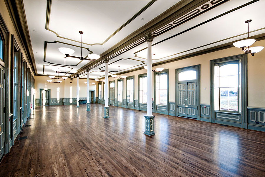 Renovated interior space of the CASO station, featuring wooden floors, teal trim, ornate columns, and updated lighting, bringing back colour and depth.