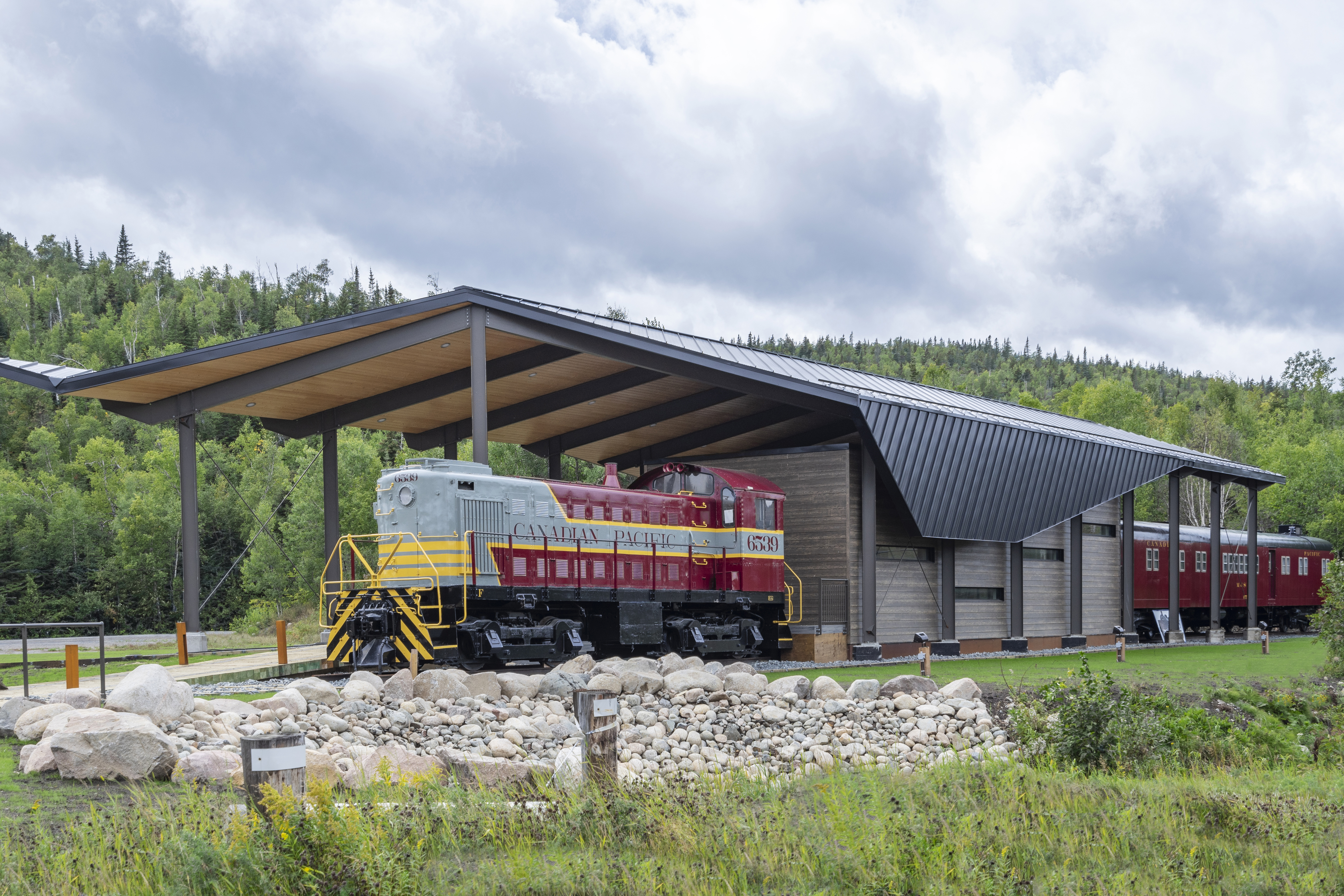 Main view of the Schreiber Discovery Centre, showcasing its modern shelter with a timber and steel structure, set against a forested backdrop.