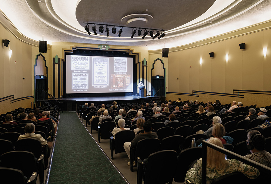 Interior view of the renovated Westdale Theatre, featuring its Art Deco design, ornate arch, and audience seated for a presentation.